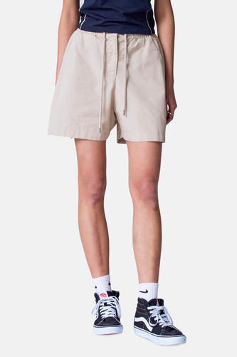 Beige court de Unwind, avec cordon et porté avec des baskets noires et des chaussettes blanches.