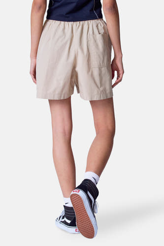 Beige court de Unwind, avec une poche arrière et porté avec des baskets noires hautes et des chaussettes blanches.