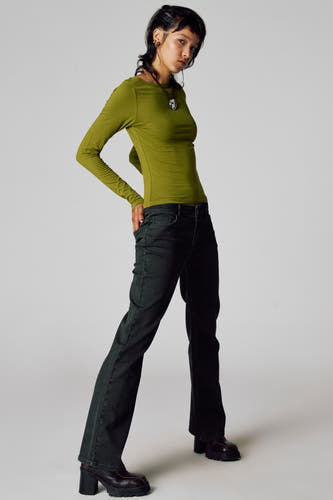 T-shirt vert avec manches longues d'Unwind, porté avec des jeans noirs et des chaussures marrons à talon.