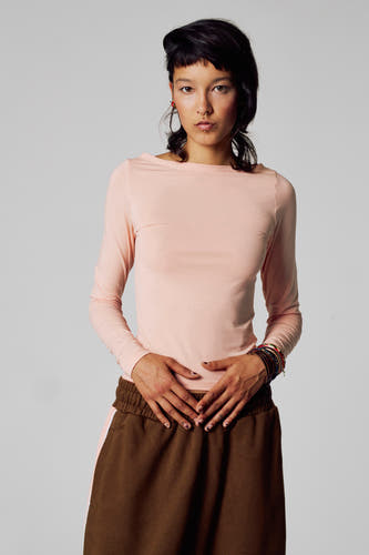 T-shirt rose à manches longues d'Unwind, avec des manches longues et associé à un pantalon marron.