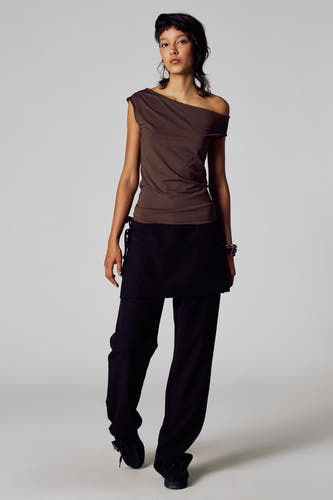 T-shirt marron à manches courtes de Unwind, porté avec une jupe noire et un pantalon.