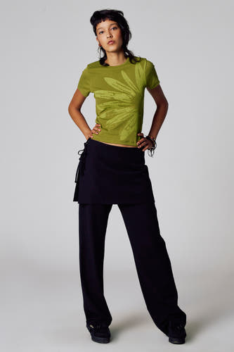 T-shirt vert avec manches courtes d'Unwind, avec un grand imprimé floral sur l'avant, associé à une jupe noire et un pantalon.