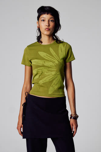 T-shirt vert avec manches courtes d'Unwind, avec un motif floral sur l'avant, associé à une jupe noire.