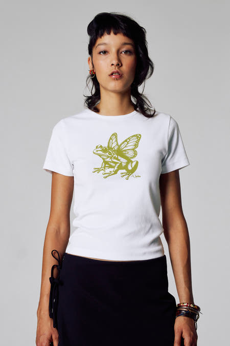 T-shirt blanc à manches courtes d'Unwind, avec imprimé de grenouille verte et de papillon, porté avec une jupe noire.