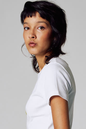 T-shirt blanc à manches courtes d'Unwind, porté par un modèle avec un piercing au nez et aux lèvres.