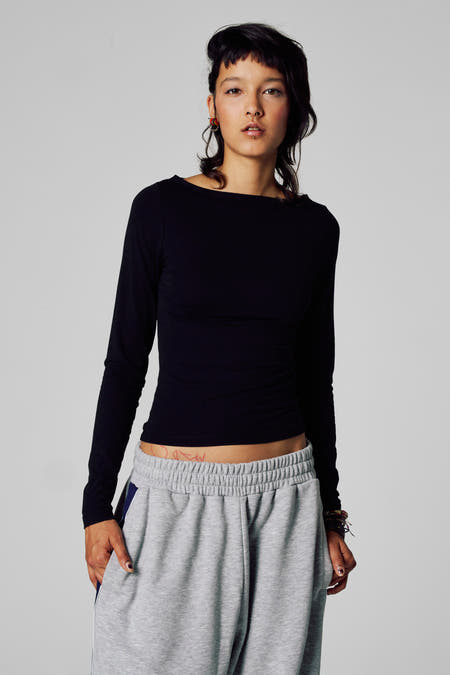 T-shirt noir à manches longues d'Unwind, avec une coupe droite et porté avec un short de jogging gris.