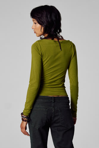 T-shirt vert avec manches longues d'Unwind, associé à un pantalon en corduroy et des bracelets.