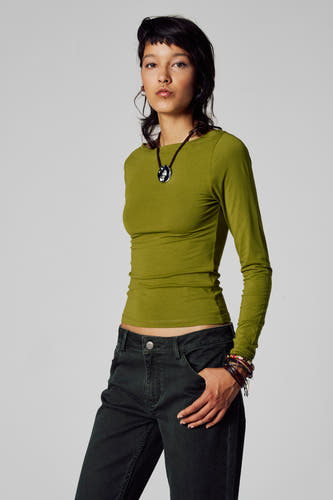 T-shirt vert avec manches longues d'Unwind, avec un col rond, associé à une chaîne et un pantalon en corduroy.