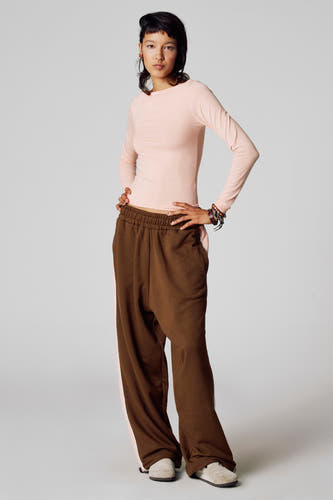 T-shirt rose à manches longues d'Unwind, porté avec un pantalon marron à des rayures roses et des chaussures de cuir suédois.