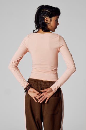 T-shirt rose à manches longues d'Unwind, avec des manches longues et un short marron.