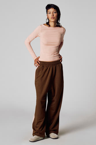 T-shirt rose à manches longues d'Unwind, avec un col montant et porté avec un pantalon de jogging brun et des mocassins en cuir.