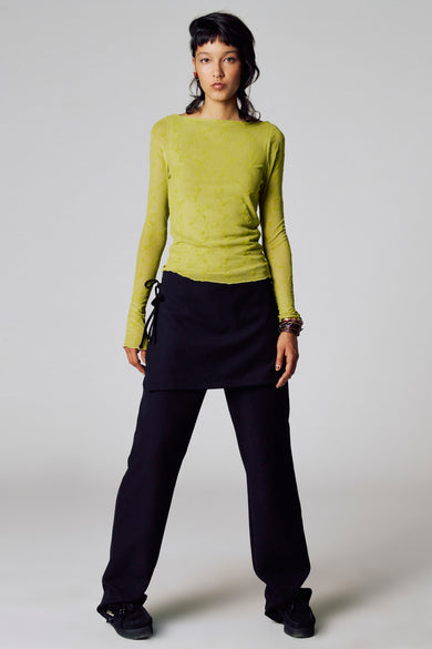 T-shirt vert avec manches longues d'Unwind, doté d'un motif subtil et porté avec un pantalon noir et une jupe.