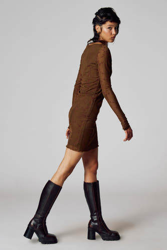 Robe brune à longues manches de Unwind, avec une subtile impression, portée avec des bottes jusqu'aux genoux.