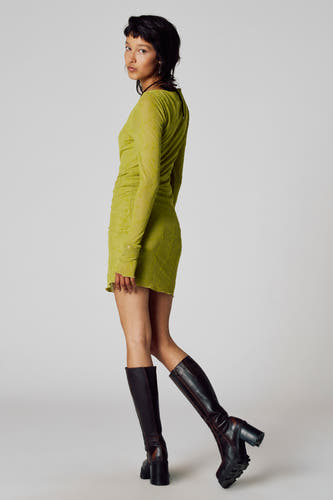 Robe verte à longues manches d'Unwind, avec un motif floral et associée à des bottes noires.