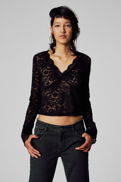 Zwart T-shirt met lange mouwen van Unwind, met kanten bovenstuk en een groene corduroy broek.
