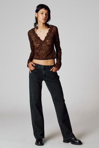 T-shirt marron à manches longues d'Unwind, avec des détails sur les bords et associé à des jeans larges et des chaussures noires.