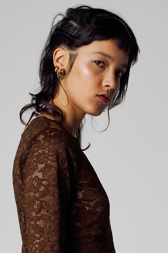 T-shirt brun à longues manches Un Unwind, avec dé dé dé; modèle avec un piercing au nez et aux lèvres.