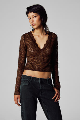 T-shirt marron à manches longues d'Unwind, avec des détails sur les bords, associé à un pantalon de corduroy noir.