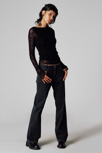 Jean gris Unwind, combiné avec une une noire transparentante des longs manches et un motif de fleurs.