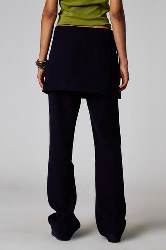 Pantalon noir d'Unwind, avec une coupe décontractée et porté avec un haut vert et des bracelets.