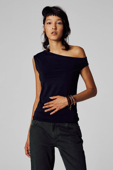 Zwart T-shirt met korte mouwen van Unwind, met een asymmetrische halslijn en gedragen met een broek van ribfluweel.

