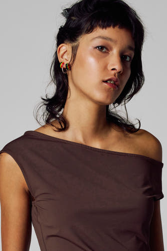 T-shirt brun à manches courtes d'Unwind, avec un col montant et porté avec des piercing.