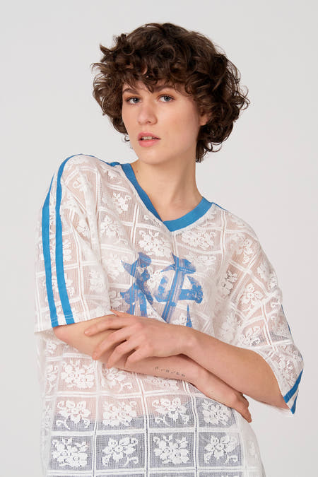 Wit T-shirt met korte mouwen van Unwind, met blauwe accenten en een semi-transparant kantpatroon.