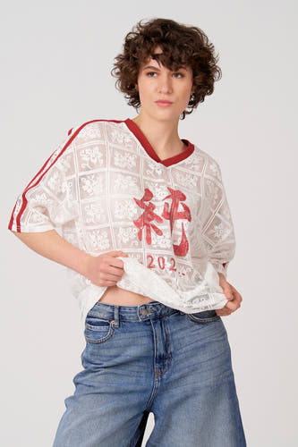 T-shirt blanc à manches courtes d'Unwind, avec motif de fleurs en dentelle et accents rouges sur les épaules, dos.