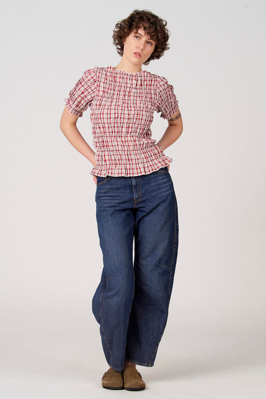 Chemisier rouge à manches courtes d'Unwind, à motif à carreaux, avec encolure élastique et coupe ample, porté avec un jean bleu.