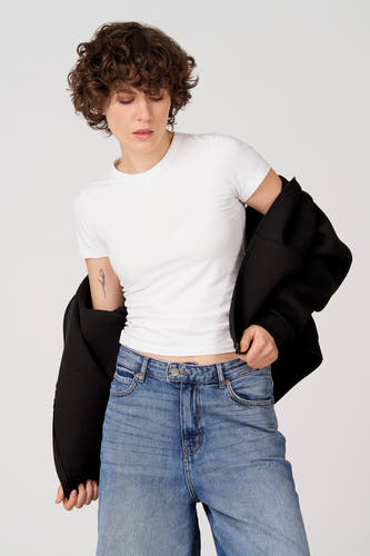 Pull noir d'Unwind, porté sur un t-shirt blanc et un jean bleu.