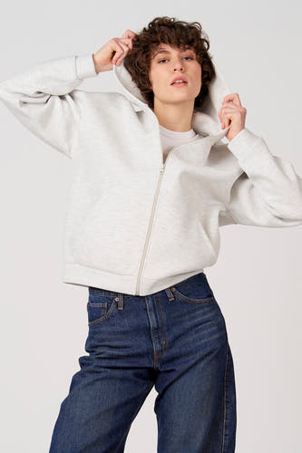 Gilet gris d'Unwind, avec capuche et manches longues, porté avec un jean foncé, vu de dos.