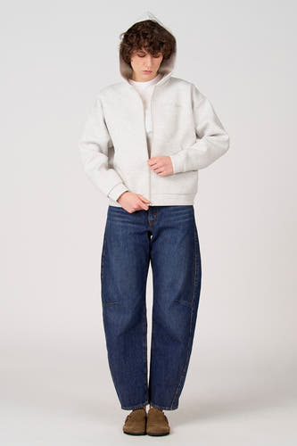 Gilet gris d'Unwind, avec capuche, fermeture éclair et combiné avec un t-shirt blanc et un jean bleu.