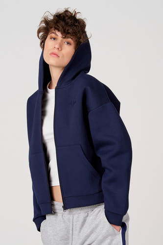 Gilet bleu d'Unwind, avec capuche, poches et un haut blanc et un jogging gris en dessous.
