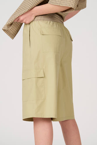 Short cargo vert clair d'Unwind avec taille élastique, poches latérales et poches à rabat, porté avec une chemise à carreaux.