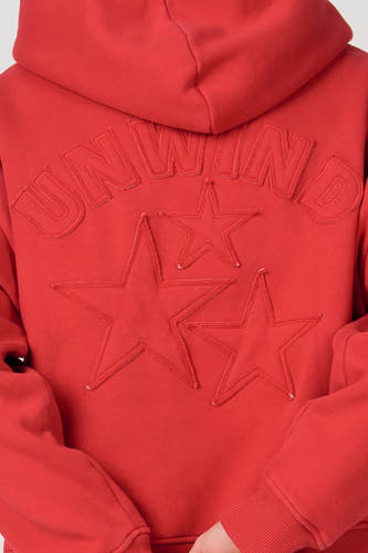 Sweat à capuche rouge d'Unwind, avec texte brodé et étoiles.
