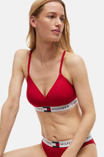 Soutien-gorge rouge de TOMMY JEANS, avec bande blanche à logo, porté par un mannequin.