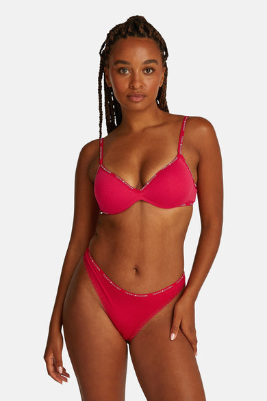 Shorty rose Tommy Jeans, avec des détails de logo le long des bords, portée par un modèle.