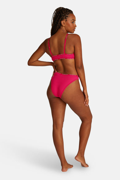 Robe de Tommy Jeans en rose, avec une ceinture élastique à logo autour, vue par derrière.