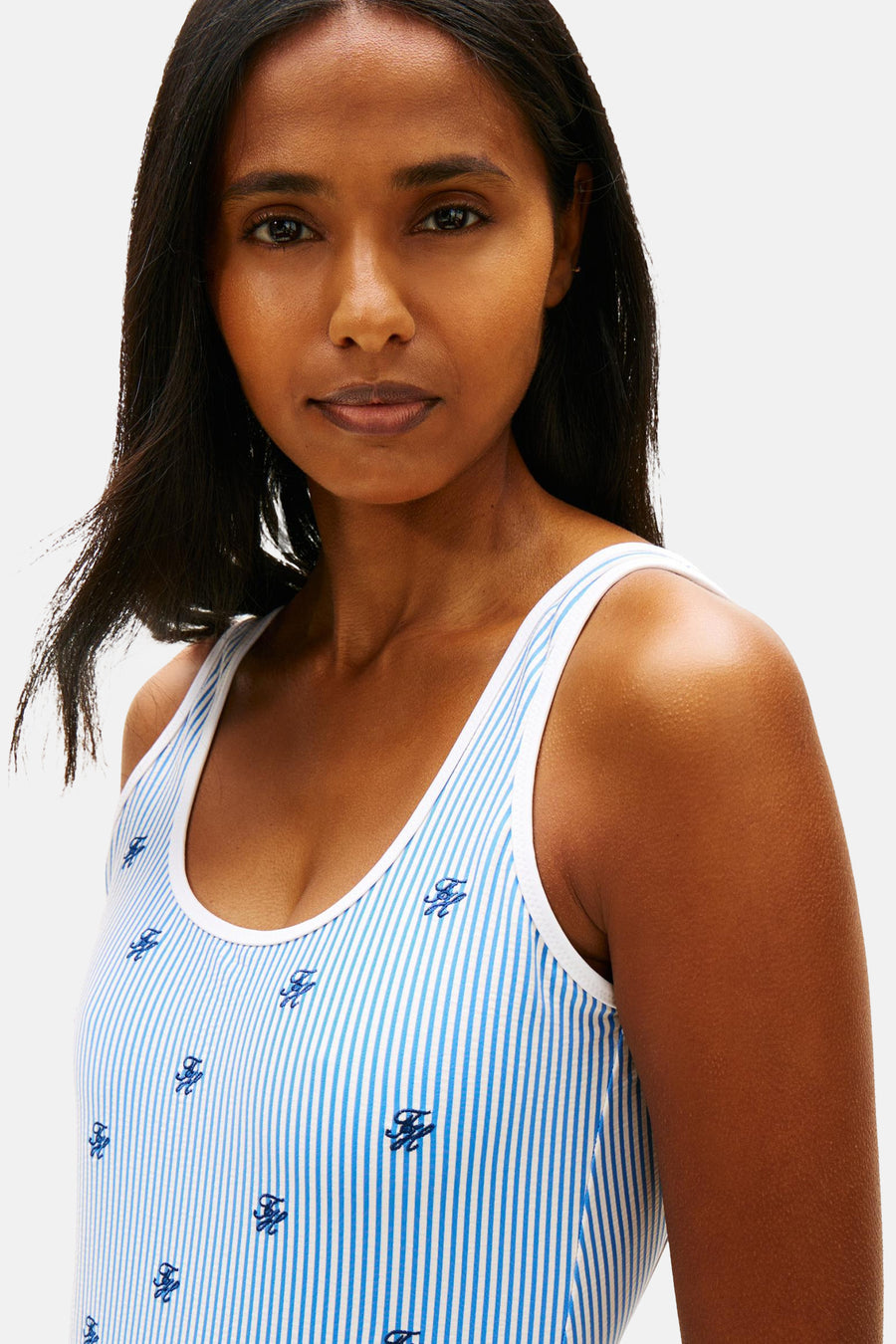 Maillot rayé bleu de TOMMY JEANS avec initiales brodées, porté par un mannequin.