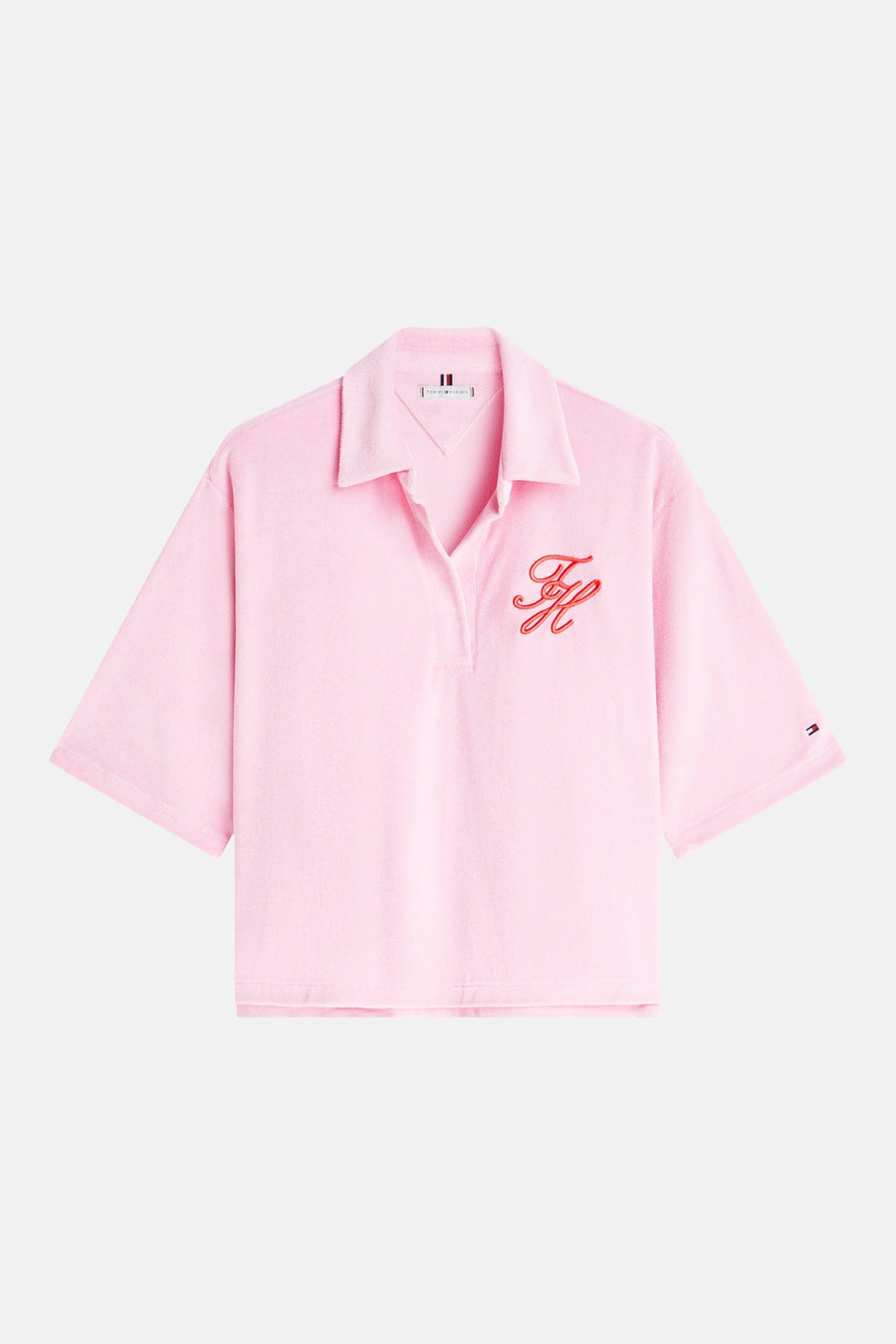Polo rose à manches courtes de TOMMY JEANS, avec une texture douce, un monogramme rouge brodé et un petit écusson drapeau sur la manche.