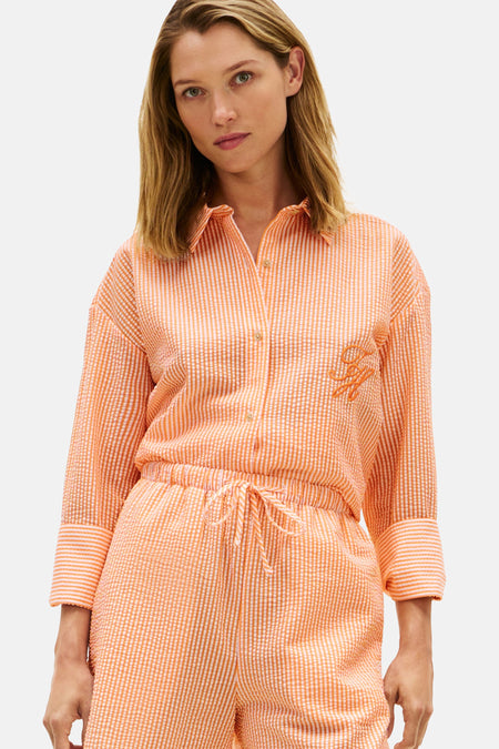 Chemise orange TOMMY JEANS, rayée avec texture seersucker et logo brodé sur la poitrine, portée avec un short assorti.