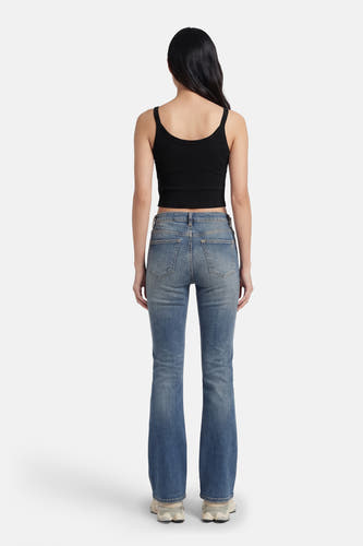 Haut noire à fines bretelles de Guess®, avec une texture côtelée, portée avec un jean évasé.