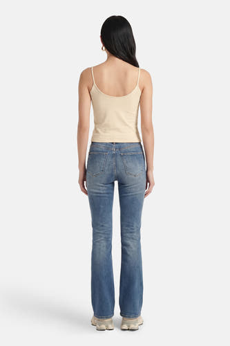 Haut beige à fines bretelles de Guess®, vue de dos, combinée avec un jean bleu et des baskets blanches.
