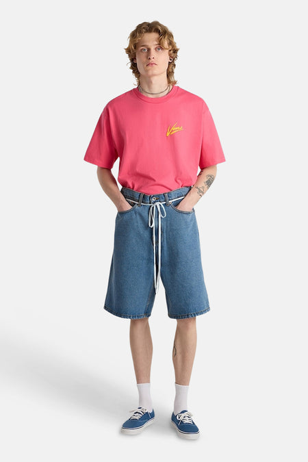 Short en jean bleu clair de VANS avec un cordon de serrage blanc, porté avec un t-shirt rose.