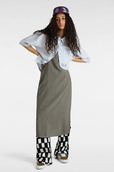 Chemise bleue à manches courtes de VANS "OFF THE WALL" portée sur une jupe grise et un pantalon rayé.