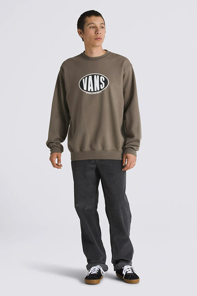 Pull-over marron de VANS "OFF THE WALL", avec un logo ovale sur la poitrine, associé à un pantalon corduroy gris et des baskets noires.