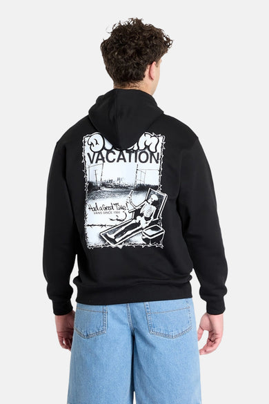 Pull-over noir avec capuche Vans, imprimé graphique sur le dos et jeans bleus.