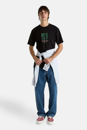 Man met zwart t-shirt met print, blauwe jeans en rood-witte sneakers.