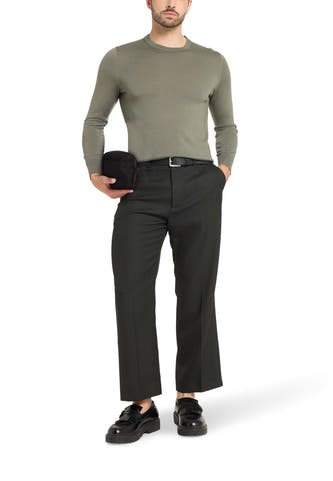 Sac à dos noir de VANS "OFF THE WALL", porté par un modèle en une chemise vert olive et un pantalon gris foncé.