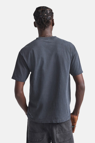 Achterkant van een persoon met grijs T-shirt en zwarte broek.